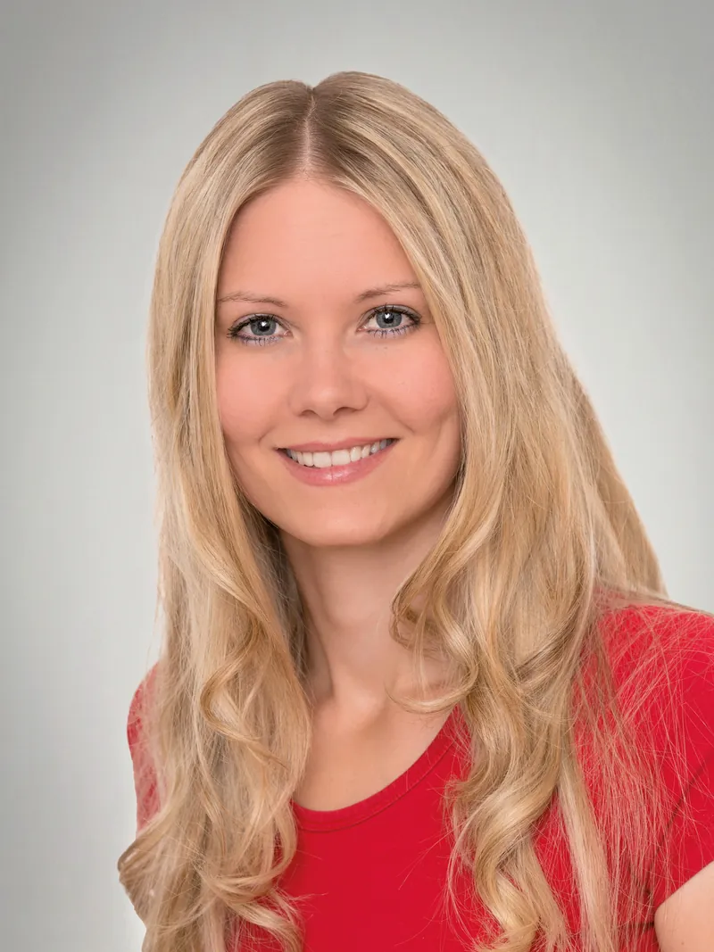 Bewerbungsbild einer Frau mit rotem Oberteil vor hellem Hintergrund