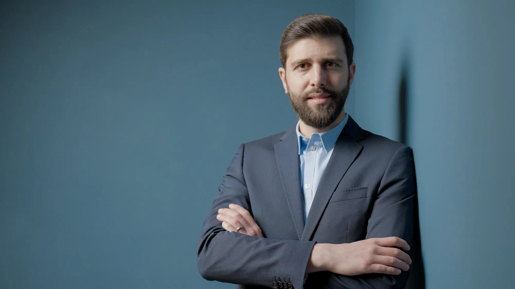 Business-Portrait eines Mannes im Anzug vor blauer Wand, fotografiert in Jena