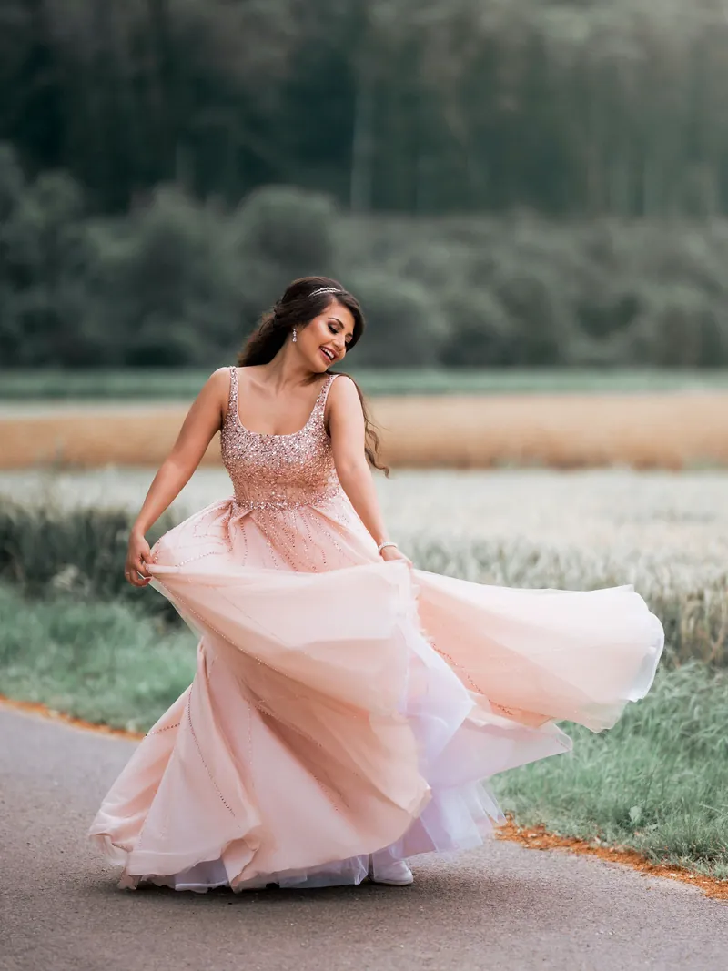 Braut im rosé Kleid dreht sich beim Paarshooting
